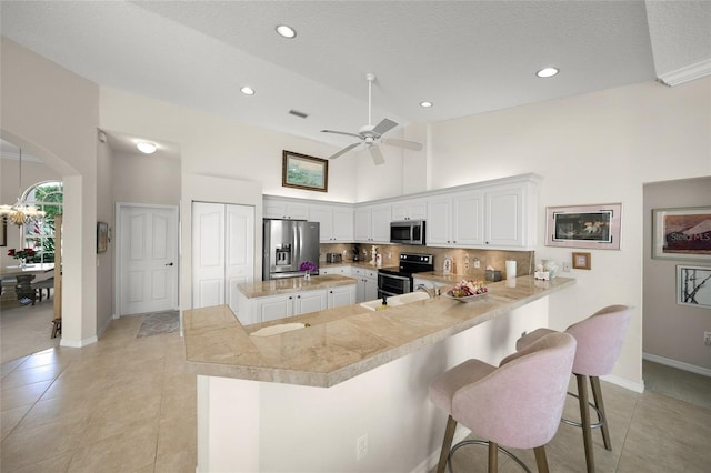 2937 Seasons Blvd, Sarasota, FL 34240 - kitchen featuring appliances with stainless steel finishes, backsplash, light countertops, a breakfast bar, and a high ceiling