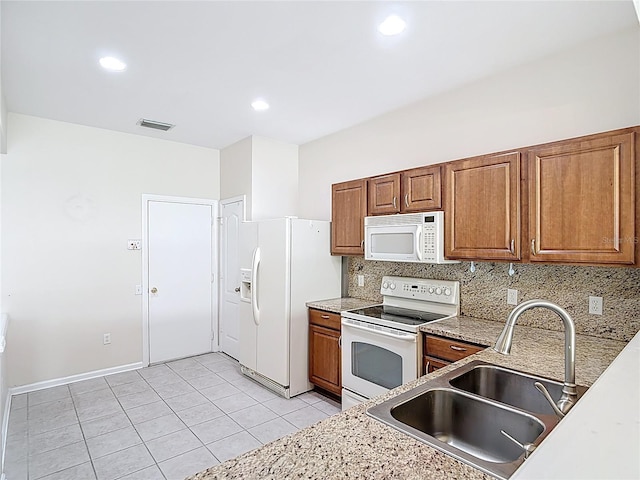 26548 Castleview Way, Wesley Chapel, FL 33544 - kitchen featuring white appliances, brown cabinets, tasteful backsplash, light tile patterned flooring, and light countertops