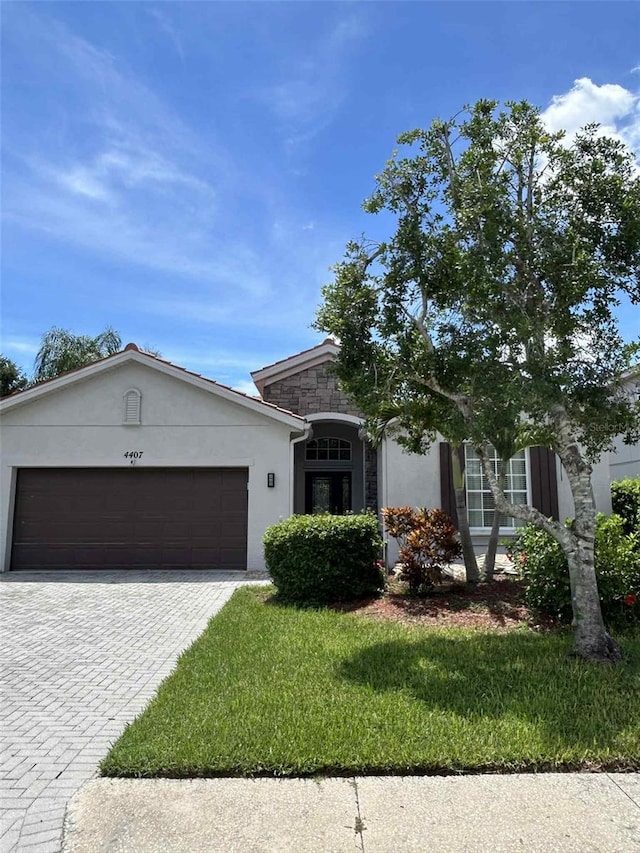 4407 67th St E, Bradenton, FL 34203 - ranch-style house with stucco siding, decorative driveway, an attached garage, and a front lawn