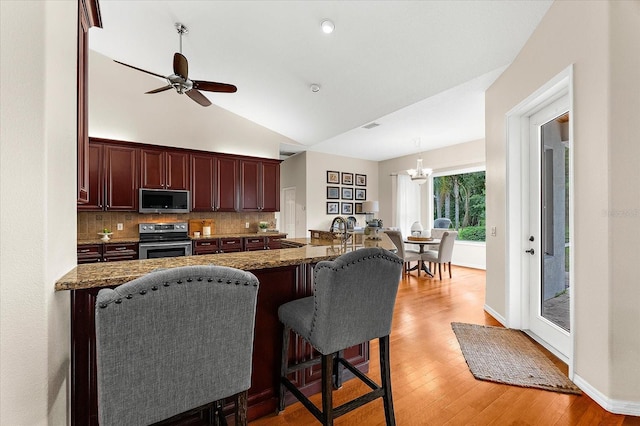 21705 67th Ave E, Bradenton, FL 34211 - kitchen featuring stainless steel appliances, a kitchen bar, backsplash, light wood-style floors, and dark stone counters