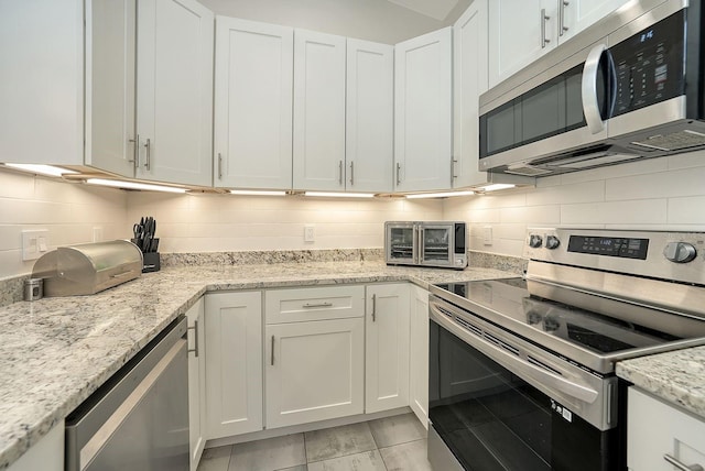 718 White Pine Tree Rd Unit 80, Venice, FL 34285 - kitchen with appliances with stainless steel finishes, white cabinetry, backsplash, and light stone counters