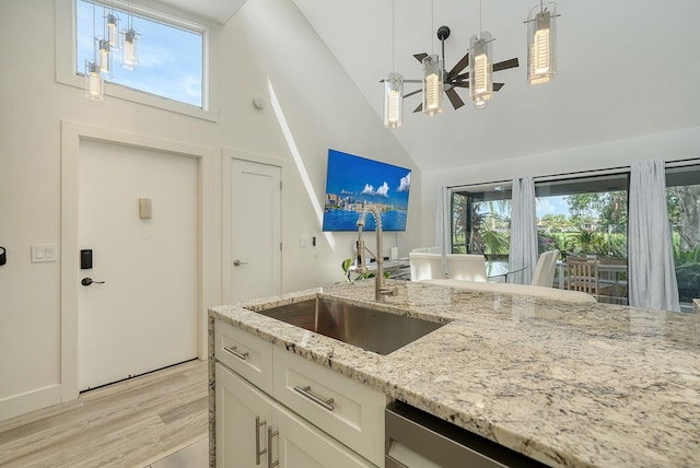 718 White Pine Tree Rd Unit 80, Venice, FL 34285 - kitchen with high vaulted ceiling, light wood-style flooring, white cabinets, light stone countertops, and decorative light fixtures