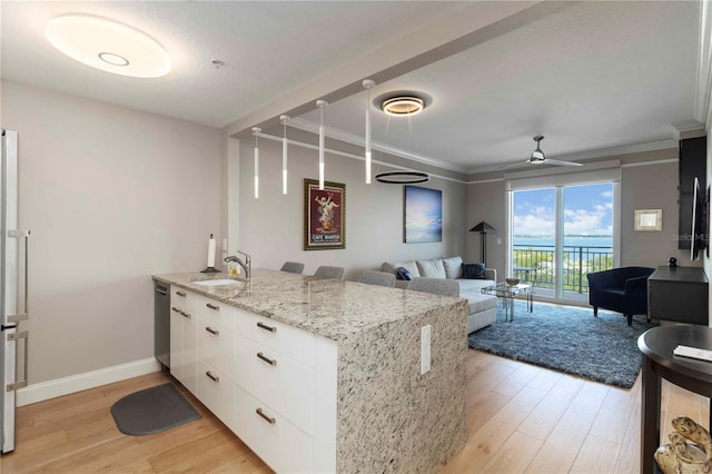 750 N Tamiami Trl Unit 1005, Sarasota, FL 34236 - kitchen with a peninsula, light wood finished floors, white cabinets, crown molding, and light stone counters