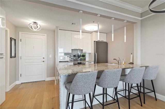 750 N Tamiami Trl Unit 1005, Sarasota, FL 34236 - kitchen featuring white microwave, freestanding refrigerator, a peninsula, ornamental molding, and a breakfast bar area