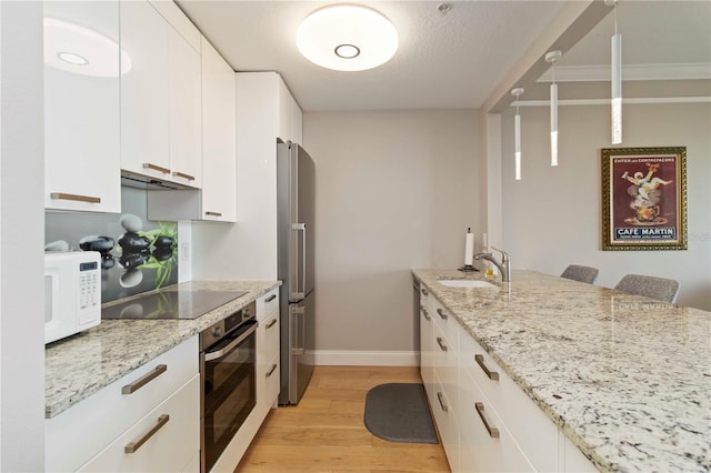 750 N Tamiami Trl Unit 1005, Sarasota, FL 34236 - kitchen with appliances with stainless steel finishes, extractor fan, light wood finished floors, white cabinets, and light stone countertops