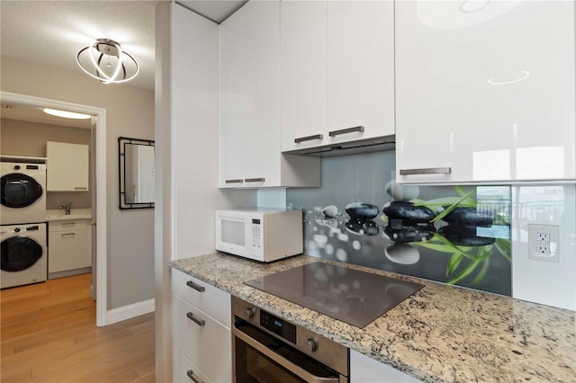 750 N Tamiami Trl Unit 1005, Sarasota, FL 34236 - kitchen with white microwave, oven, white cabinets, black electric stovetop, and light wood-style floors