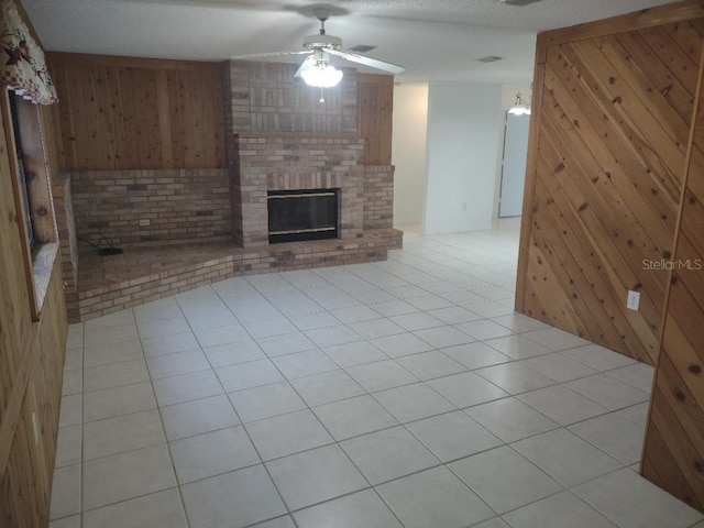 8851 S Brittany Path, Inverness, FL 34452 - unfurnished living room with a ceiling fan, wooden walls, a brick fireplace, and light tile patterned floors