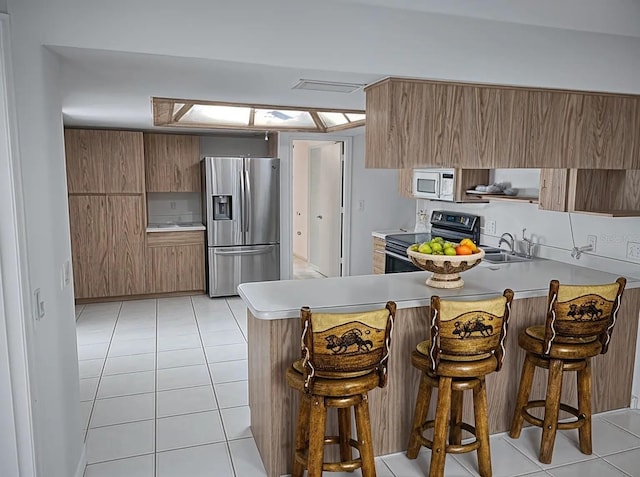 8851 S Brittany Path, Inverness, FL 34452 - kitchen with stainless steel fridge, electric range, white microwave, a peninsula, and light countertops