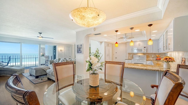 1 Benjamin Franklin Dr Unit 93, Sarasota, FL 34236 - dining space featuring ceiling fan, ornamental molding, a raised ceiling, wood finished floors, and arched walkways