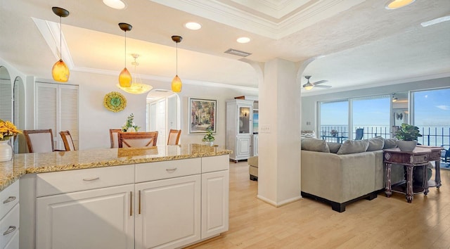 1 Benjamin Franklin Dr Unit 93, Sarasota, FL 34236 - kitchen featuring arched walkways, crown molding, light wood-style flooring, a tray ceiling, and a ceiling fan