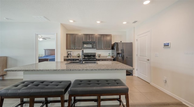 3813 Willow Branch Pl, Palmetto, FL 34221 - kitchen featuring black appliances, a kitchen breakfast bar, dark brown cabinetry, an island with sink, and light tile patterned floors