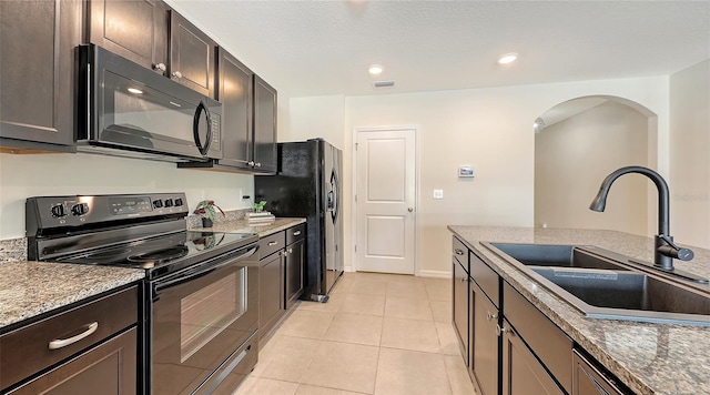 3813 Willow Branch Pl, Palmetto, FL 34221 - kitchen featuring black appliances, arched walkways, light tile patterned floors, dark brown cabinetry, and recessed lighting