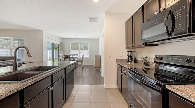 3813 Willow Branch Pl, Palmetto, FL 34221 - kitchen with black appliances, stone counters, dark brown cabinetry, and light tile patterned flooring