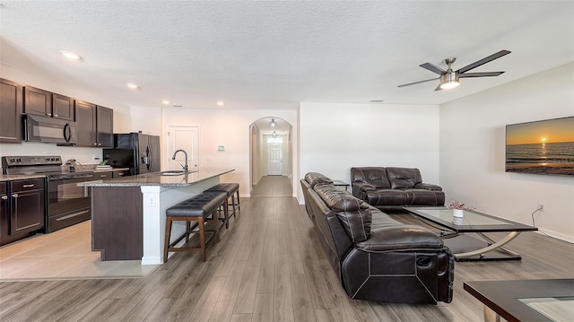 3813 Willow Branch Pl, Palmetto, FL 34221 - living room with arched walkways, a ceiling fan, light wood-style flooring, a textured ceiling, and recessed lighting