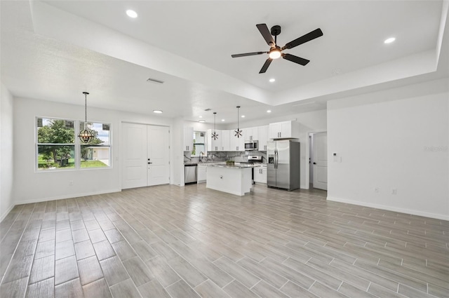 4855 Dragon St, North Port, FL 34288 - unfurnished living room with ceiling fan, recessed lighting, light wood-style floors, a chandelier, and a tray ceiling
