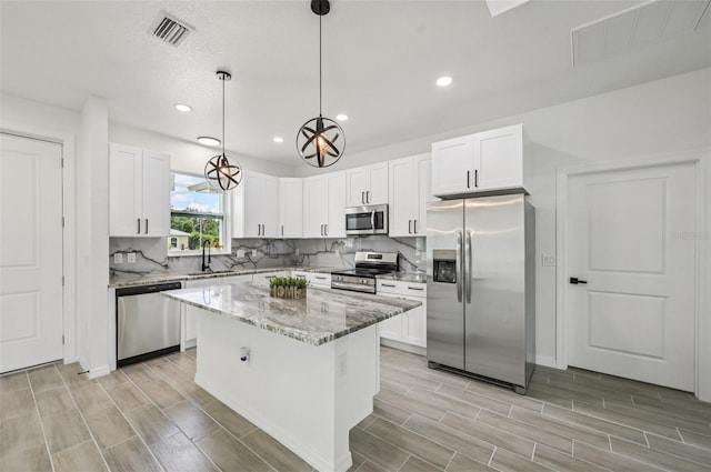4855 Dragon St, North Port, FL 34288 - kitchen featuring appliances with stainless steel finishes, light stone countertops, white cabinetry, wood tiled floors, and recessed lighting