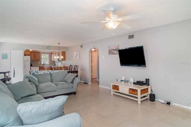 5400 34th St W Unit 5G, Bradenton, FL 34210 - living area featuring arched walkways, ceiling fan, a textured ceiling, light tile patterned floors, and a chandelier
