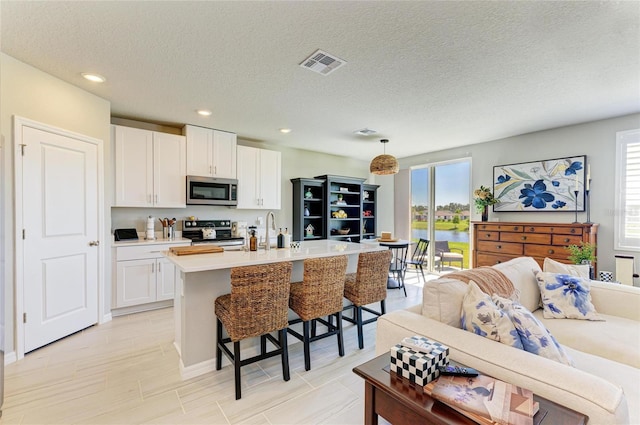 7160 Amelia River Dr, Parrish, FL 34219 - kitchen featuring appliances with stainless steel finishes, white cabinetry, a kitchen bar, a center island with sink, and recessed lighting