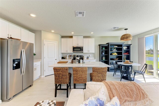 7160 Amelia River Dr, Parrish, FL 34219 - kitchen with appliances with stainless steel finishes, light countertops, white cabinets, a textured ceiling, and an island with sink