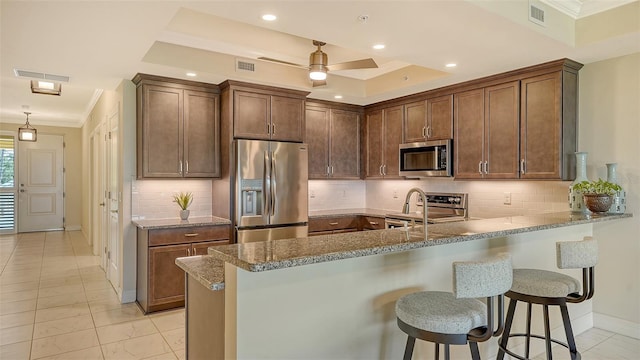 250 Hidden Bay Dr Unit 302, Osprey, FL 34229 - kitchen featuring appliances with stainless steel finishes, ornamental molding, a peninsula, a breakfast bar, and decorative backsplash