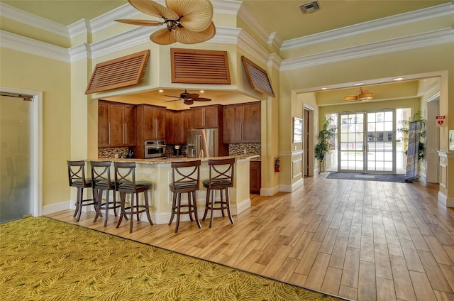 250 Hidden Bay Dr Unit 302, Osprey, FL 34229 - kitchen featuring a ceiling fan, a peninsula, light wood-style floors, crown molding, and a breakfast bar