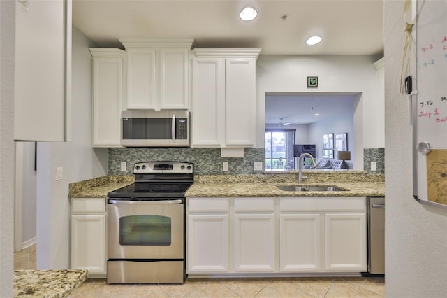 7344 Skybird Rd, Bradenton, FL 34209 - kitchen featuring appliances with stainless steel finishes, backsplash, white cabinetry, light stone countertops, and recessed lighting