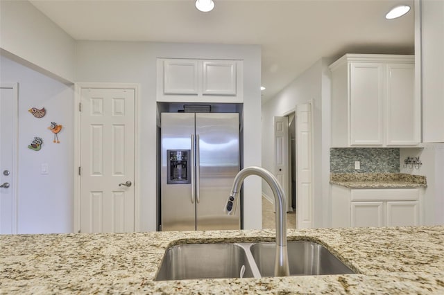 7344 Skybird Rd, Bradenton, FL 34209 - kitchen with stainless steel fridge, white cabinetry, light stone countertops, recessed lighting, and backsplash