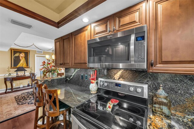 5855 Midnight Pass Rd Unit 416, Sarasota, FL 34242 - kitchen featuring stainless steel appliances, crown molding, wood finished floors, dark countertops, and decorative backsplash