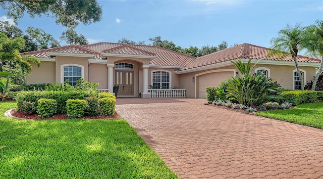 6206 Stillwater Ct, University Park, FL 34201 - mediterranean / spanish-style house featuring an attached garage, a tile roof, stucco siding, decorative driveway, and a front lawn