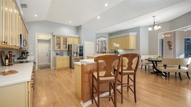 6206 Stillwater Ct, University Park, FL 34201 - kitchen with stainless steel appliances, light wood-style flooring, a center island, a breakfast bar, and lofted ceiling