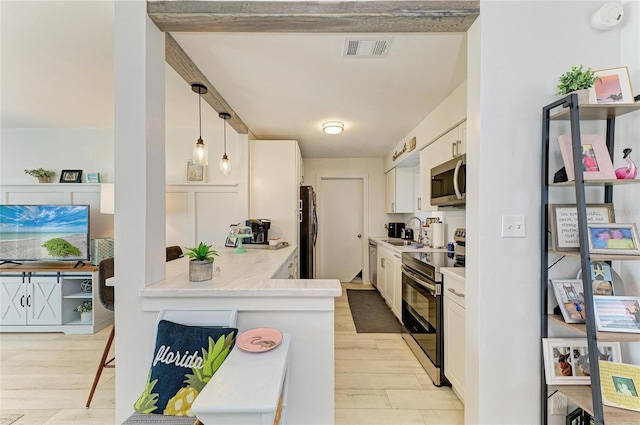 237 Saxon Cir, Venice, FL 34293 - kitchen with stainless steel appliances, light wood-type flooring, white cabinetry, light countertops, and hanging light fixtures