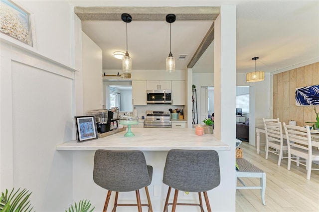 237 Saxon Cir, Venice, FL 34293 - kitchen with stainless steel appliances, a breakfast bar, a peninsula, light wood-style flooring, and wooden walls