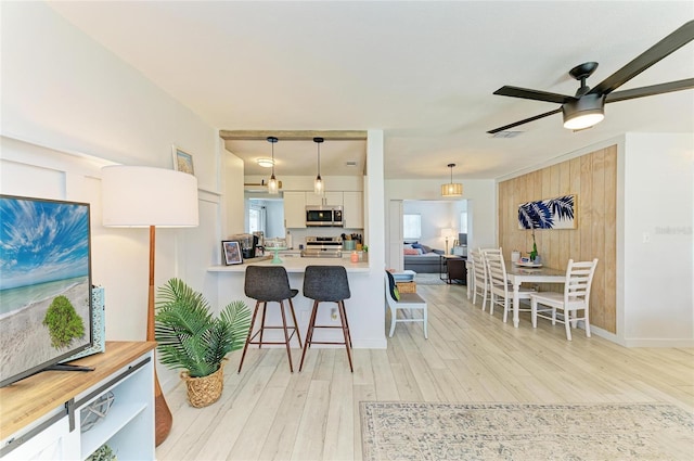 237 Saxon Cir, Venice, FL 34293 - kitchen featuring stainless steel microwave, range with electric cooktop, a kitchen breakfast bar, light countertops, and light wood-style flooring