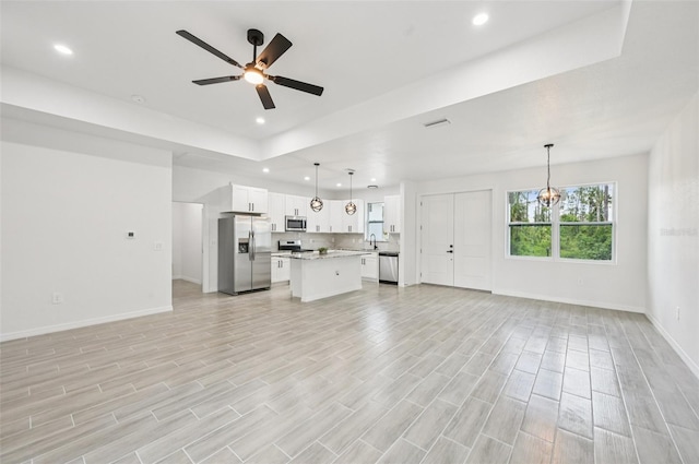 2523 Hagerick Ln, North Port, FL 34288 - unfurnished living room featuring ceiling fan, recessed lighting, light wood-style flooring, a raised ceiling, and a chandelier