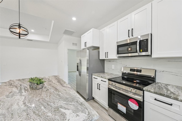 2523 Hagerick Ln, North Port, FL 34288 - kitchen with appliances with stainless steel finishes, white cabinets, light stone counters, tasteful backsplash, and recessed lighting