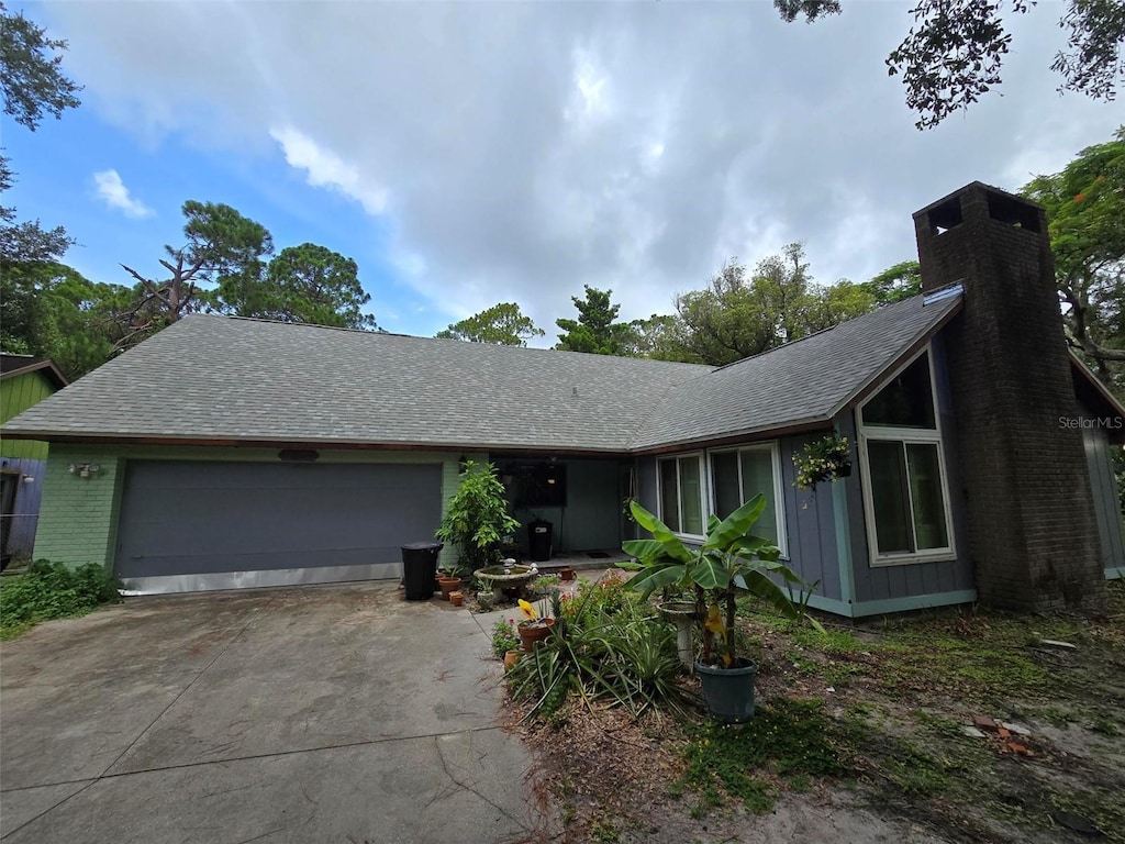 4607 Mink Rd, Sarasota, FL 34235 - view of front of home featuring driveway, an attached garage, a chimney, and a shingled roof