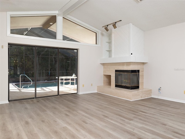 8260 Berkeley Manor Blvd, Spring Hill, FL 34606 - unfurnished living room with wood finished floors, a tile fireplace, and track lighting