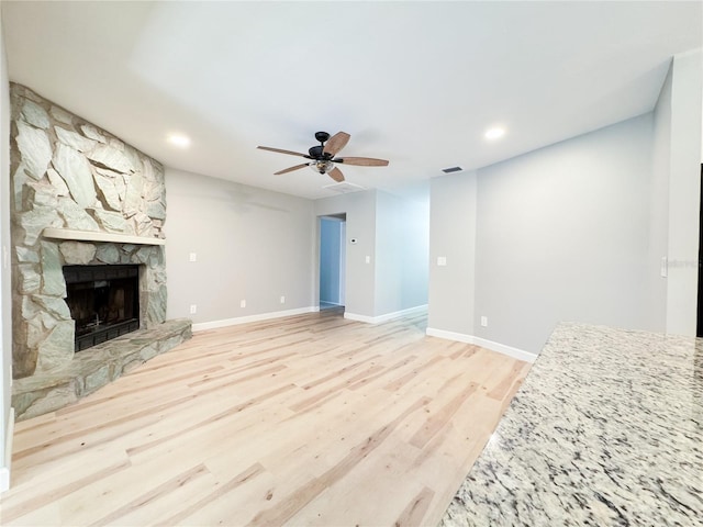 4913 32nd St E, Bradenton, FL 34203 - unfurnished living room with light wood-style flooring, ceiling fan, a stone fireplace, and recessed lighting