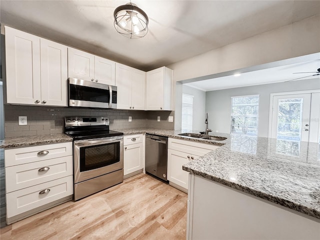 4913 32nd St E, Bradenton, FL 34203 - kitchen with appliances with stainless steel finishes, light wood finished floors, white cabinetry, and tasteful backsplash