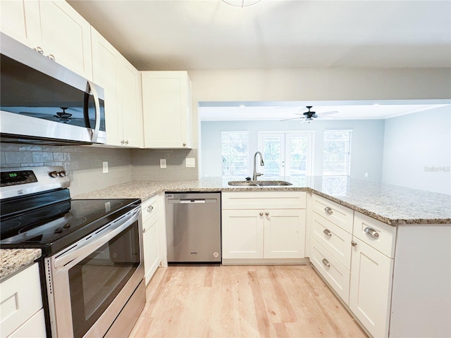 4913 32nd St E, Bradenton, FL 34203 - kitchen with stainless steel appliances, a ceiling fan, light wood finished floors, white cabinetry, and light stone countertops