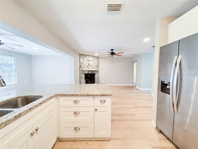 4913 32nd St E, Bradenton, FL 34203 - kitchen with stainless steel refrigerator with ice dispenser, ceiling fan, light stone countertops, a stone fireplace, and recessed lighting