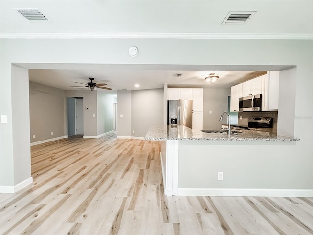 4913 32nd St E, Bradenton, FL 34203 - kitchen featuring appliances with stainless steel finishes, a peninsula, light stone counters, white cabinets, and light wood finished floors