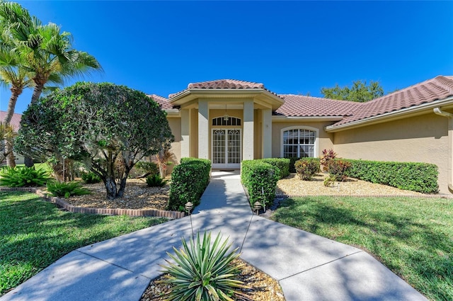 8315 Eagle Xing, Sarasota, FL 34241 - doorway to property featuring stucco siding, a tile roof, and a lawn