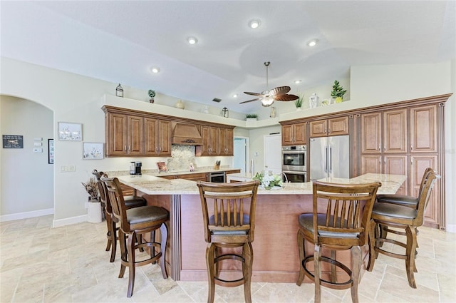 8315 Eagle Xing, Sarasota, FL 34241 - kitchen with stainless steel appliances, premium range hood, arched walkways, a kitchen bar, and lofted ceiling