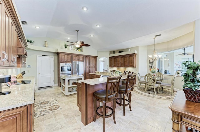 8315 Eagle Xing, Sarasota, FL 34241 - kitchen featuring a kitchen island with sink, ceiling fan, stainless steel appliances, a breakfast bar, and light stone finish flooring