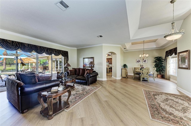 8315 Eagle Xing, Sarasota, FL 34241 - living area featuring arched walkways, ornamental molding, light wood-style flooring, healthy amount of natural light, and a chandelier