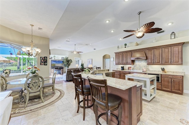 8315 Eagle Xing, Sarasota, FL 34241 - kitchen featuring a ceiling fan, a large island with sink, custom range hood, stone tile flooring, and open floor plan