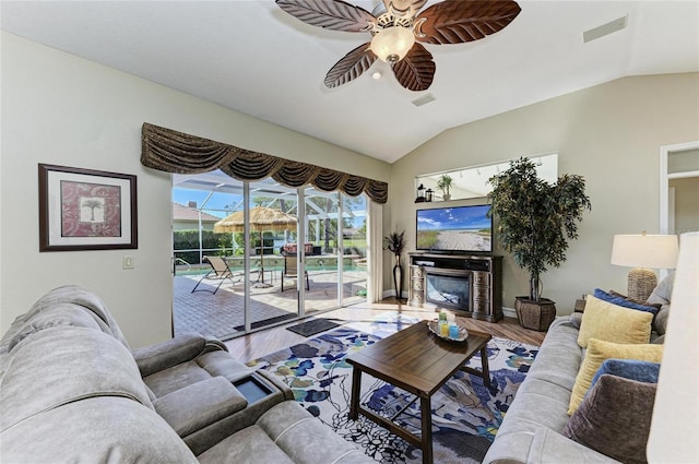 8315 Eagle Xing, Sarasota, FL 34241 - living room featuring ceiling fan, wood finished floors, vaulted ceiling, and a glass covered fireplace