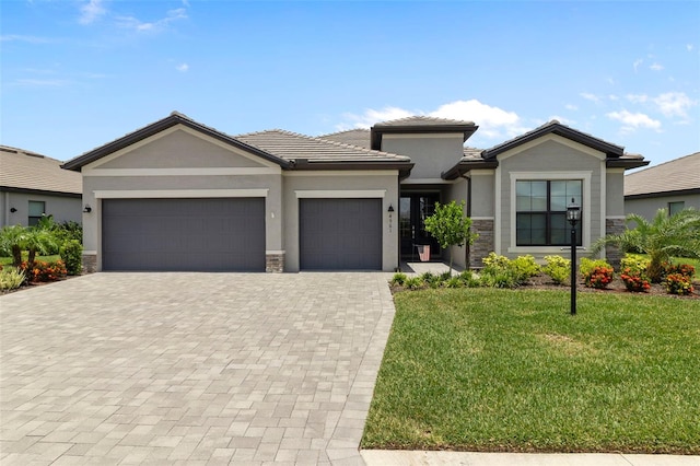 4961 Seafoam Trl, Bradenton, FL 34211 - view of front of home featuring a garage, decorative driveway, a front lawn, stone siding, and a tile roof