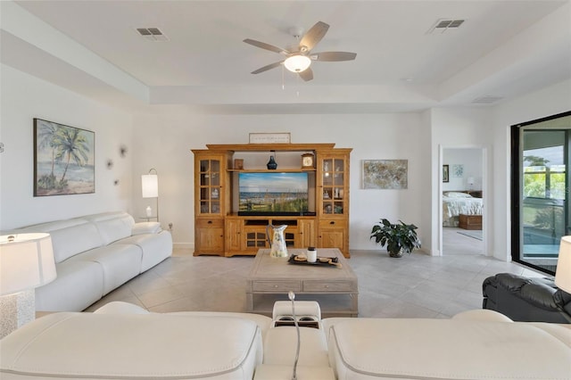 4961 Seafoam Trl, Bradenton, FL 34211 - living room featuring a tray ceiling, light tile patterned floors, and a ceiling fan